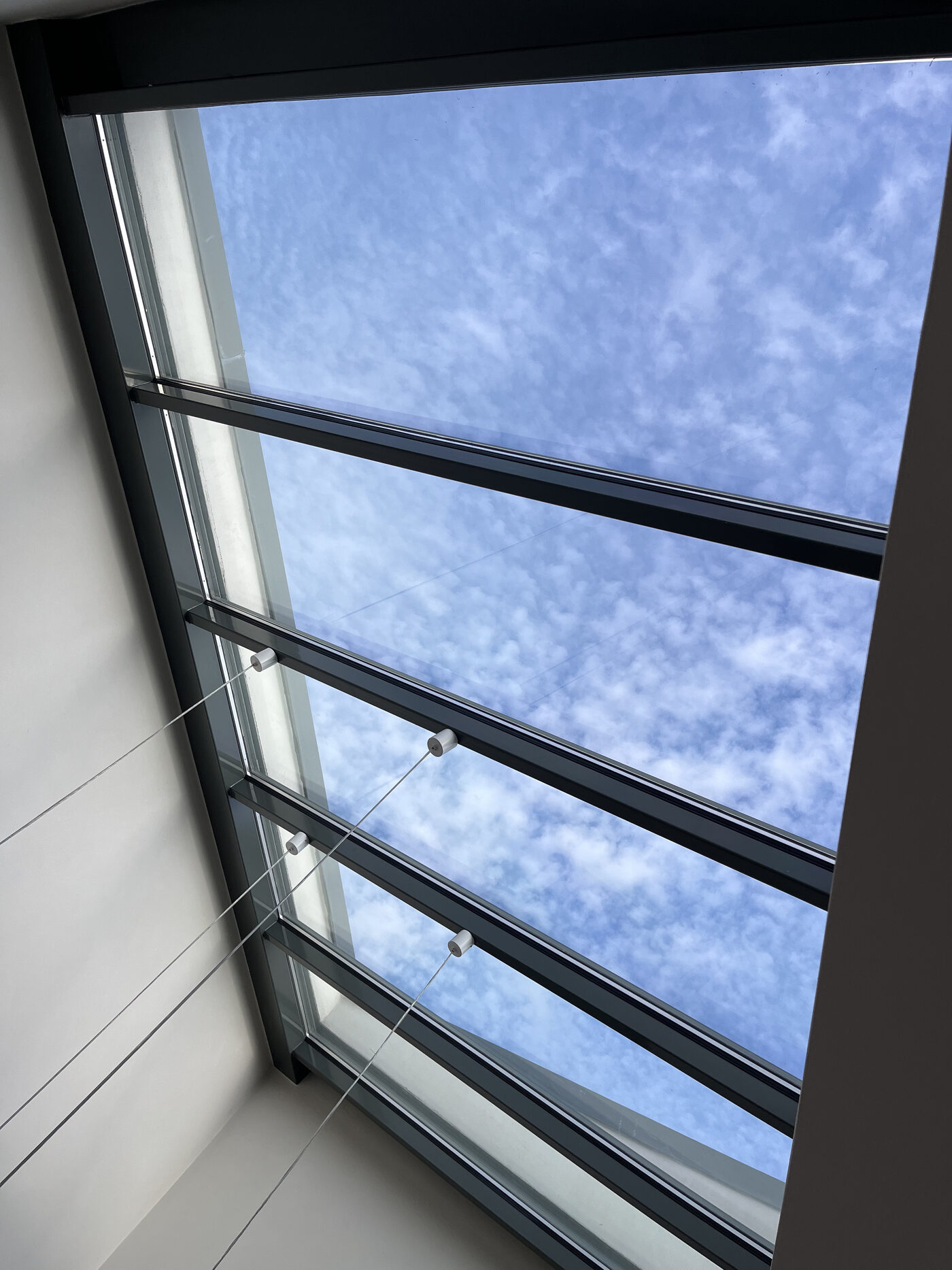 Modernes Dachfenster mit Sonnenschutzfolie und Stahlseil-Detail